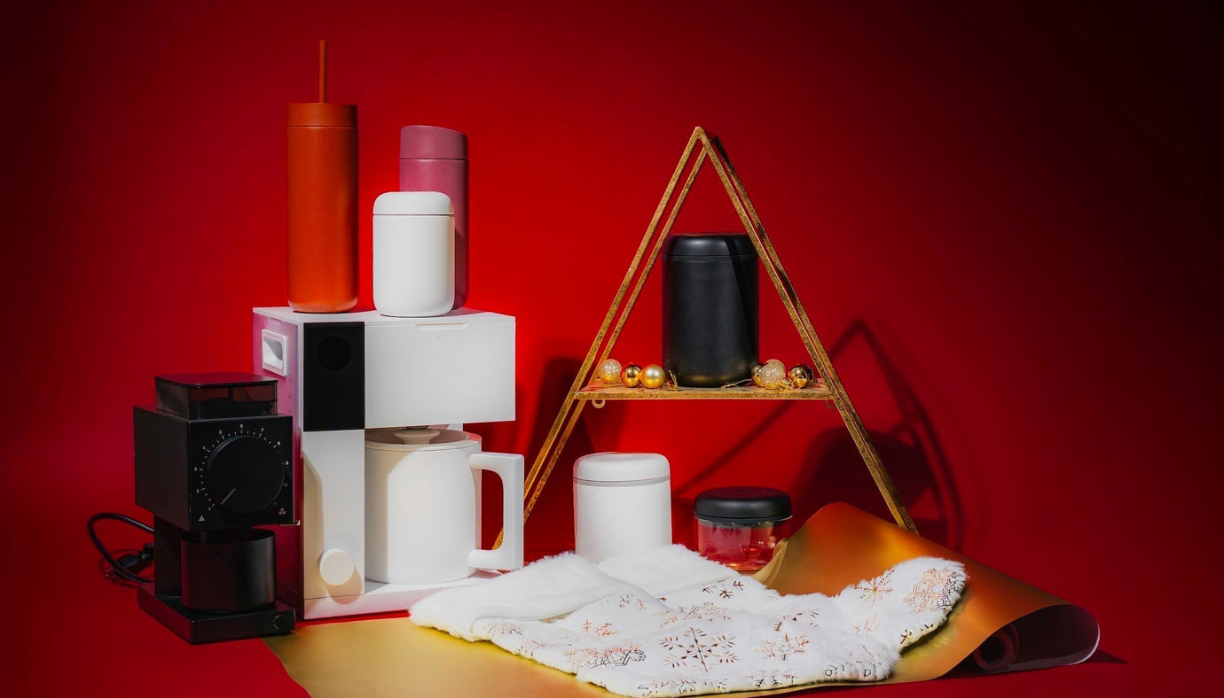 Fellow Aiden, Ode Brew Grinder, and travel tumblers stacked against a red background