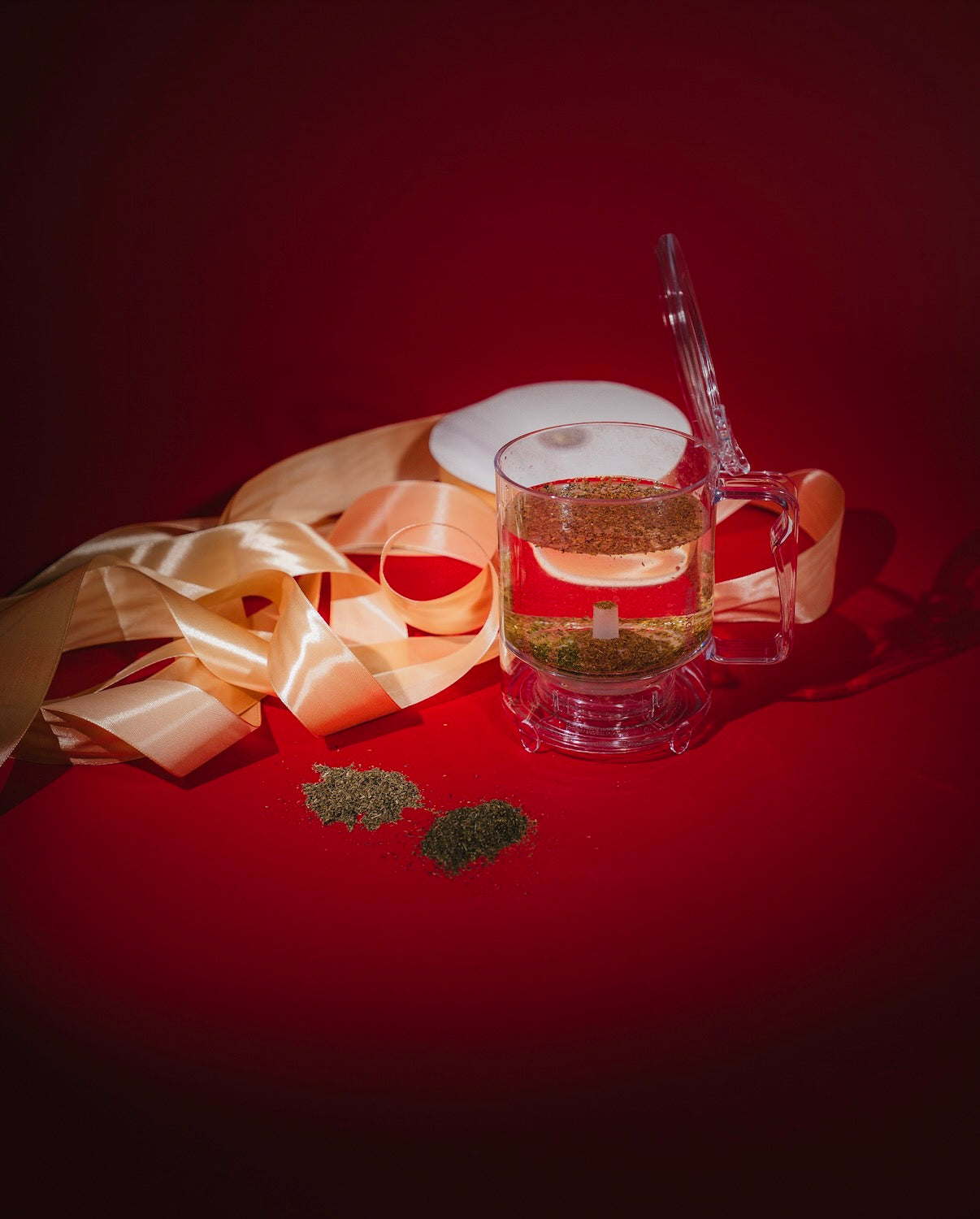 HandyBrew Tea Brewer against a red background with gold ribbons